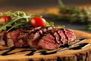 "Raw shaved steak on a cutting board with a knife and paper towel, demonstrating proper preparation techniques without washing.