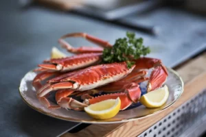 Delicious frozen snow crab legs steamed and served with melted butter and lemon wedges on a plate.