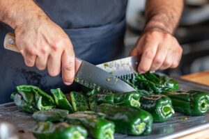 A set of essential tools including a paring knife, tongs, and spoon used for preparing and stuffing poblano peppers.

