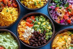 "Taco bowl ingredients including ground beef, rice, beans, cheese, salsa, and guacamole in a colorful bowl"

