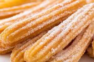 Baked churros dusted with cinnamon sugar on a plate for a healthier alternative to traditional deep-fried churros.

