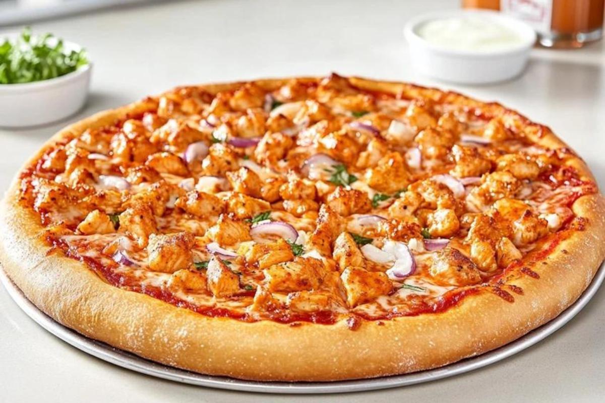 A close-up of Domino's Buffalo Chicken Pizza with grilled chicken, melted cheese, and spicy buffalo sauce on a golden crust.