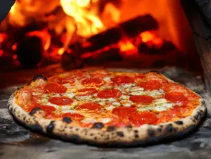 What is the best temperature to cook a pizza? 3 Pizza baking in a home oven with crispy crust and perfectly melted cheese, showing the best temperature to cook pizza for great results.