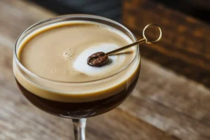 An espresso martini in a glass garnished with coffee beans, showcasing the rich, dark color and creamy froth on top.