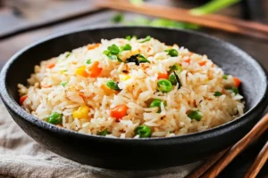 A close-up of golden, crispy fried rice in a wok with vegetables and protein, highlighting the perfect texture. 