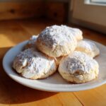 A plate piled high with soft, powdered Italian Ricotta Cookies, dusted generously with confectioners' sugar.
