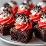 Close-up of Santa Hat Brownie Bites, decorated with red frosting, whipped cream, and sprinkles.