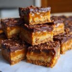 Close-up of stacked Biscoff Caramel Sticky Toffee Bars, showing layers of caramel and chocolate.