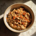 Bowl of homemade high-protein turkey cat food with visible shredded turkey and carrots.