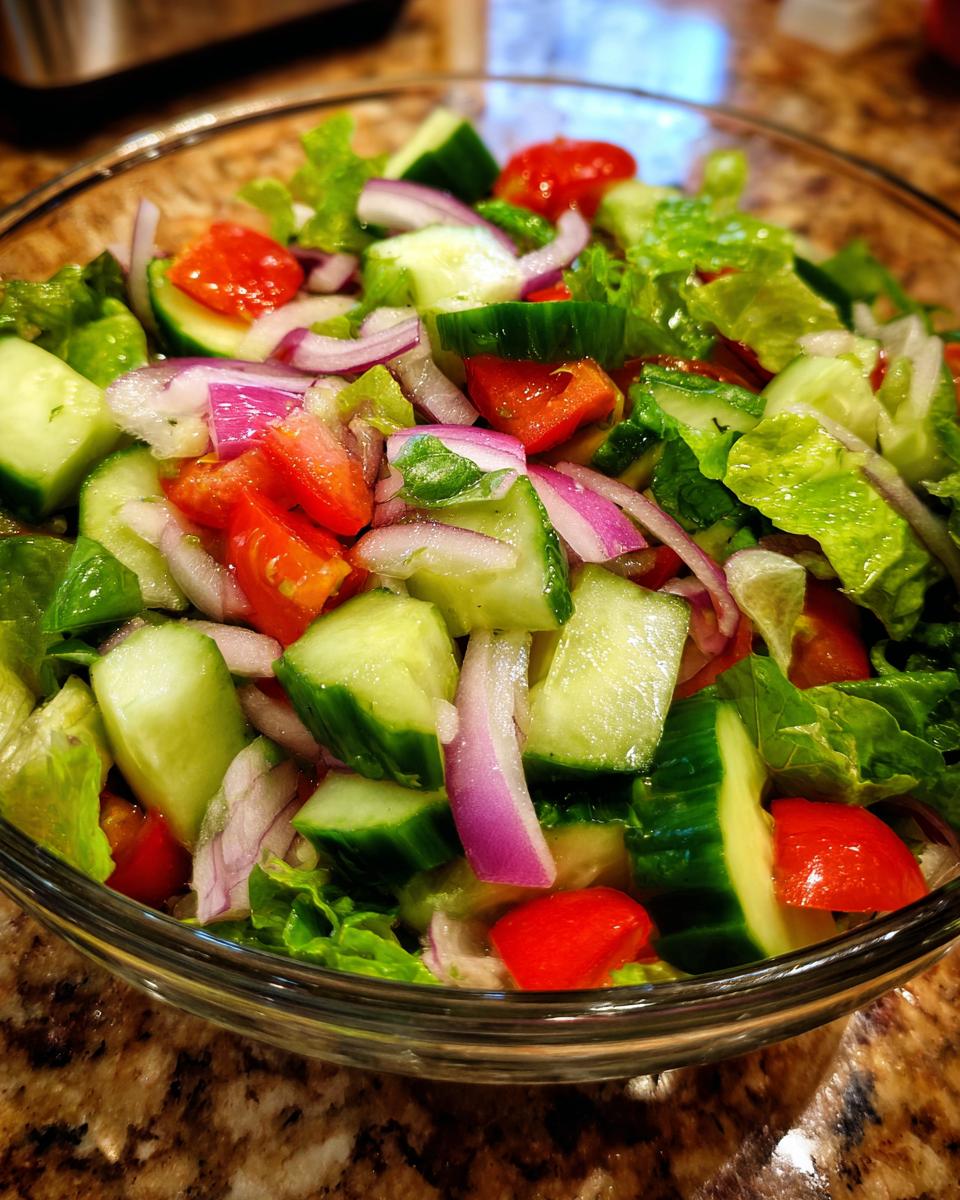 Close-up of a fresh salad with cucumbers, tomatoes, red onion, and lettuce; perfect for a 15-Minute Salad.