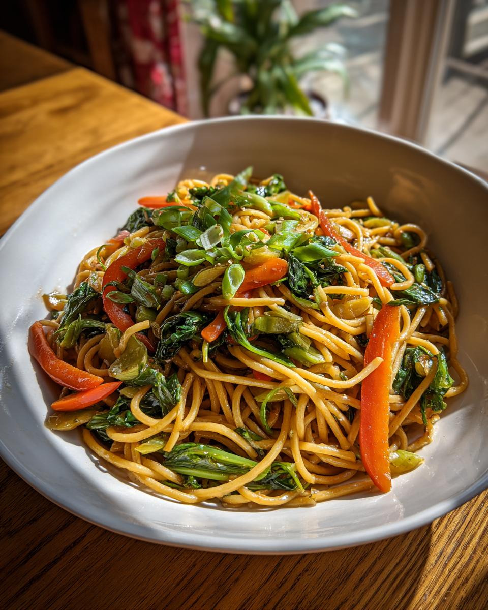 Close-up of a bowl of Asian pasta salad with noodles, vegetables, and green onions.