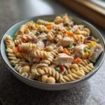 Close-up of a bowl of high protein pasta salad with chicken, vegetables, and chickpeas.