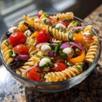 Close-up of a bowl of quick and easy Italian pasta salad, featuring pasta, tomatoes, mozzarella, and basil.