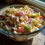 Close-up of a bowl of pasta salad classic with rotini pasta, vegetables, and creamy dressing.