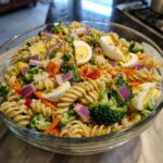 A large bowl of pasta salad Easter with rotini pasta, vegetables, and hard-boiled eggs.