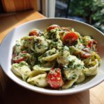 Close-up of a bowl of pasta salad green goddess with cherry tomatoes and fresh herbs.