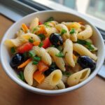 A bowl of delicious pasta salad no cheese with olives, tomatoes, and vegetables.