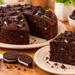 Homemade four-ingredient Oreo steamed cake sliced on a ceramic plate with chocolate sandwich cookies nearby.
