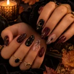 Witchy and chic Halloween nail art with black, burgundy and gold details