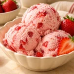 Creamy homemade strawberry ice cream with fresh strawberries and a smooth pink texture.